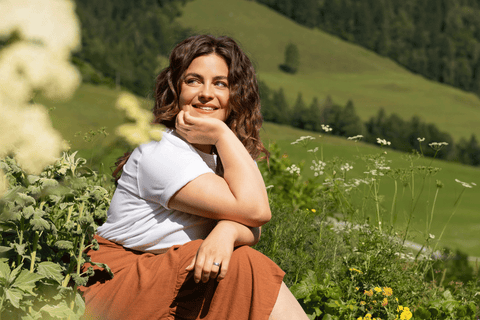 Frau sitzt im Blumengarten